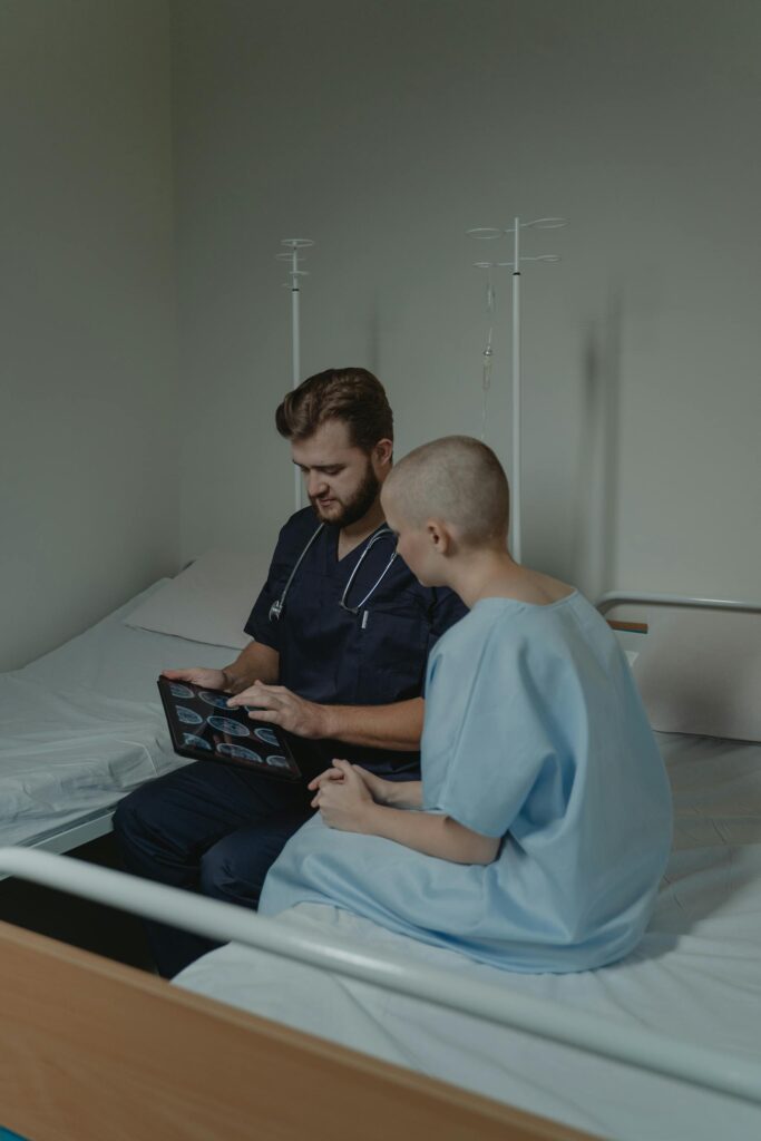 Doctor and patient in hospital room discussing CT scan results on a digital tablet.