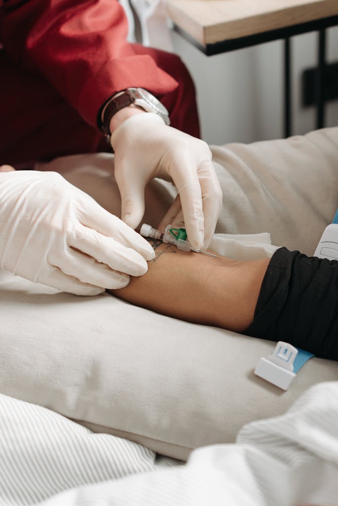 Doctor wearing gloves giving an injection to a patient's arm in a medical setting.